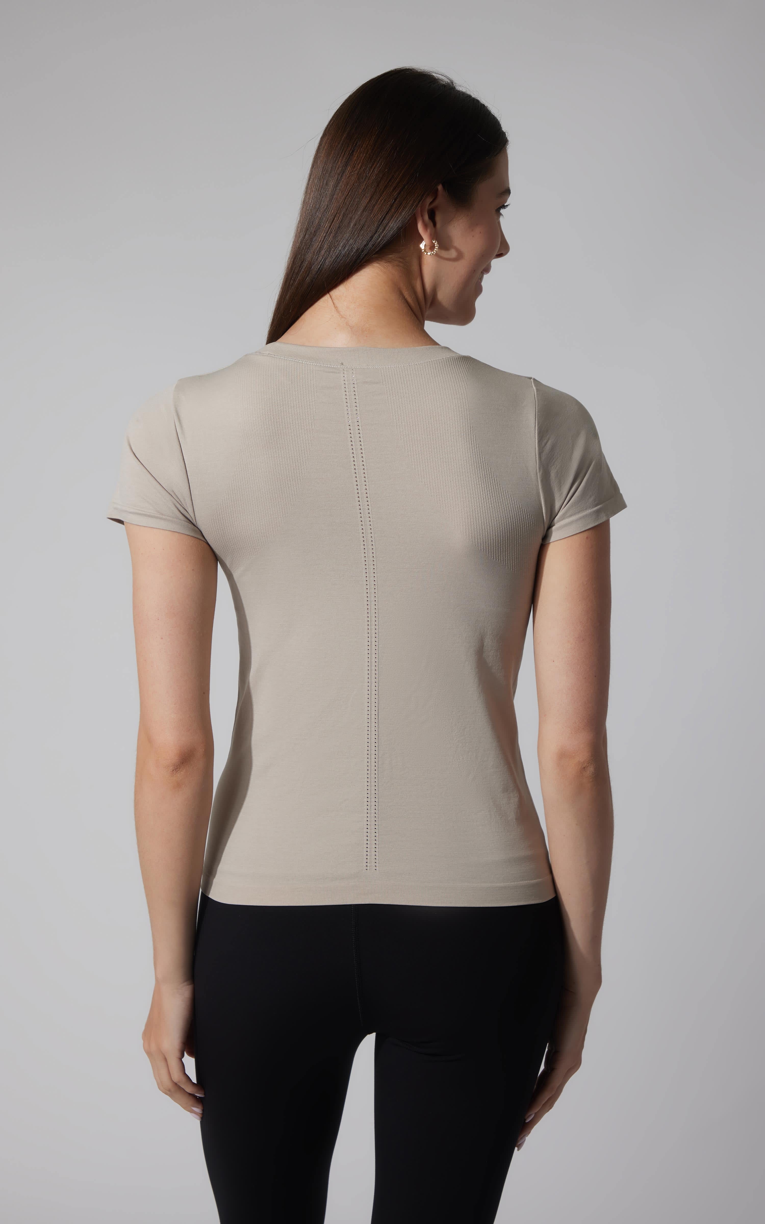 Seamless short sleeve tee in soft beige with full-length fit on woman from the back.