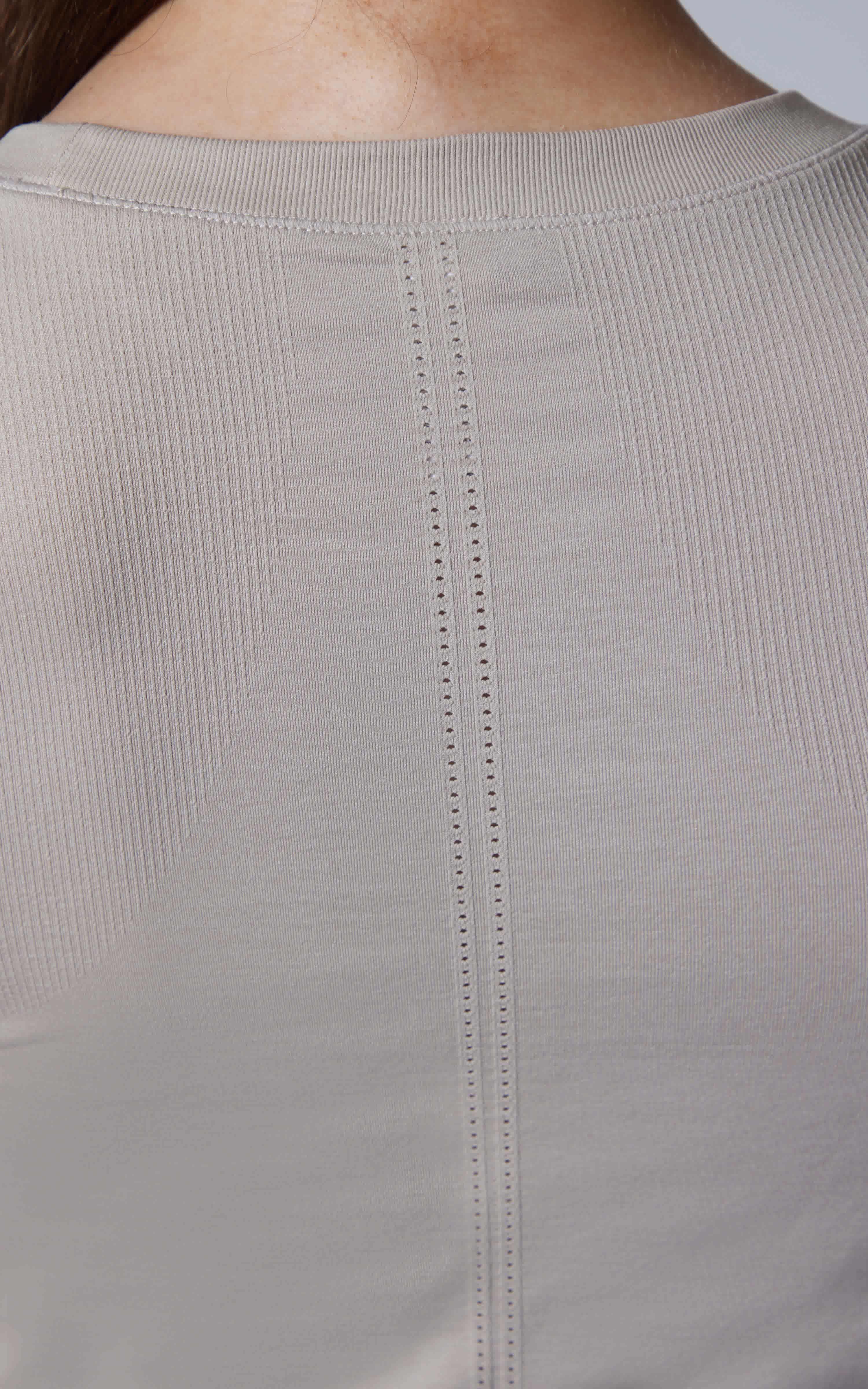 Close-up of seamless light green short sleeve tee with subtle vertical stitch detail at the neckline.
