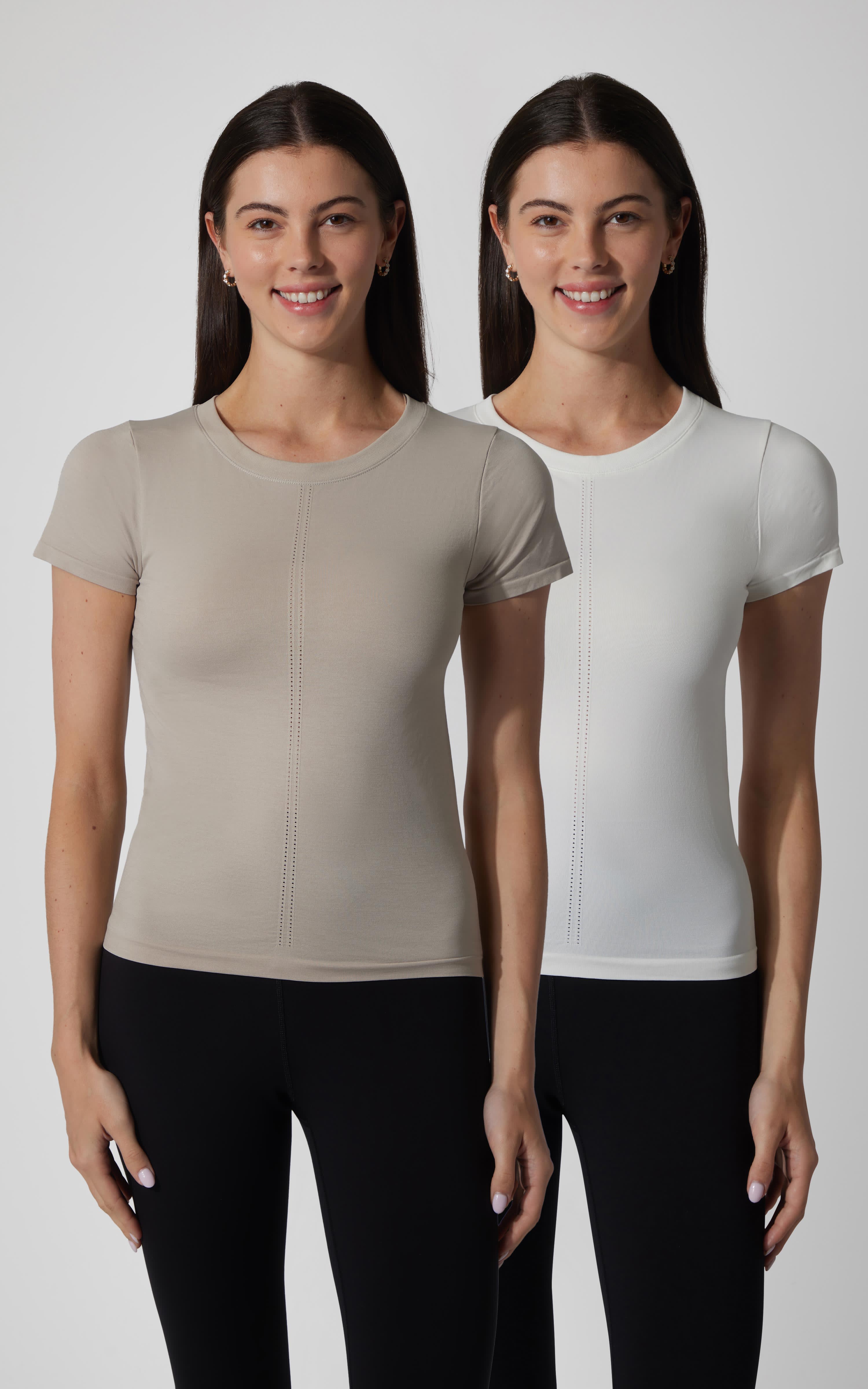 Two women wearing seamless short sleeve full length tees in light taupe and white, paired with black pants.