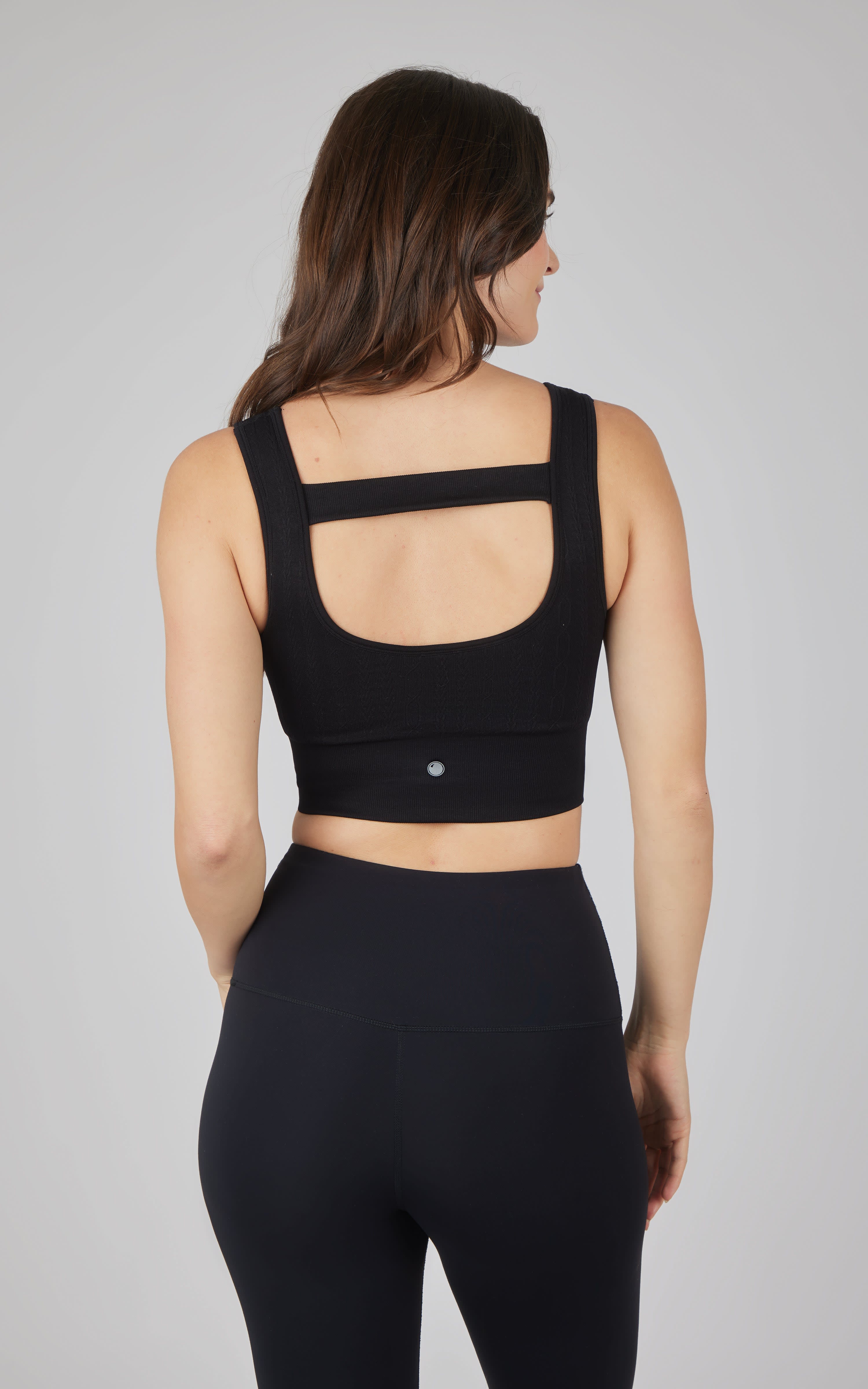 Black seamless cable knit bra top with wide straps and open back cutout detail.