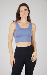 Seamless blue cable knit bra top with scoop neck worn with black leggings.