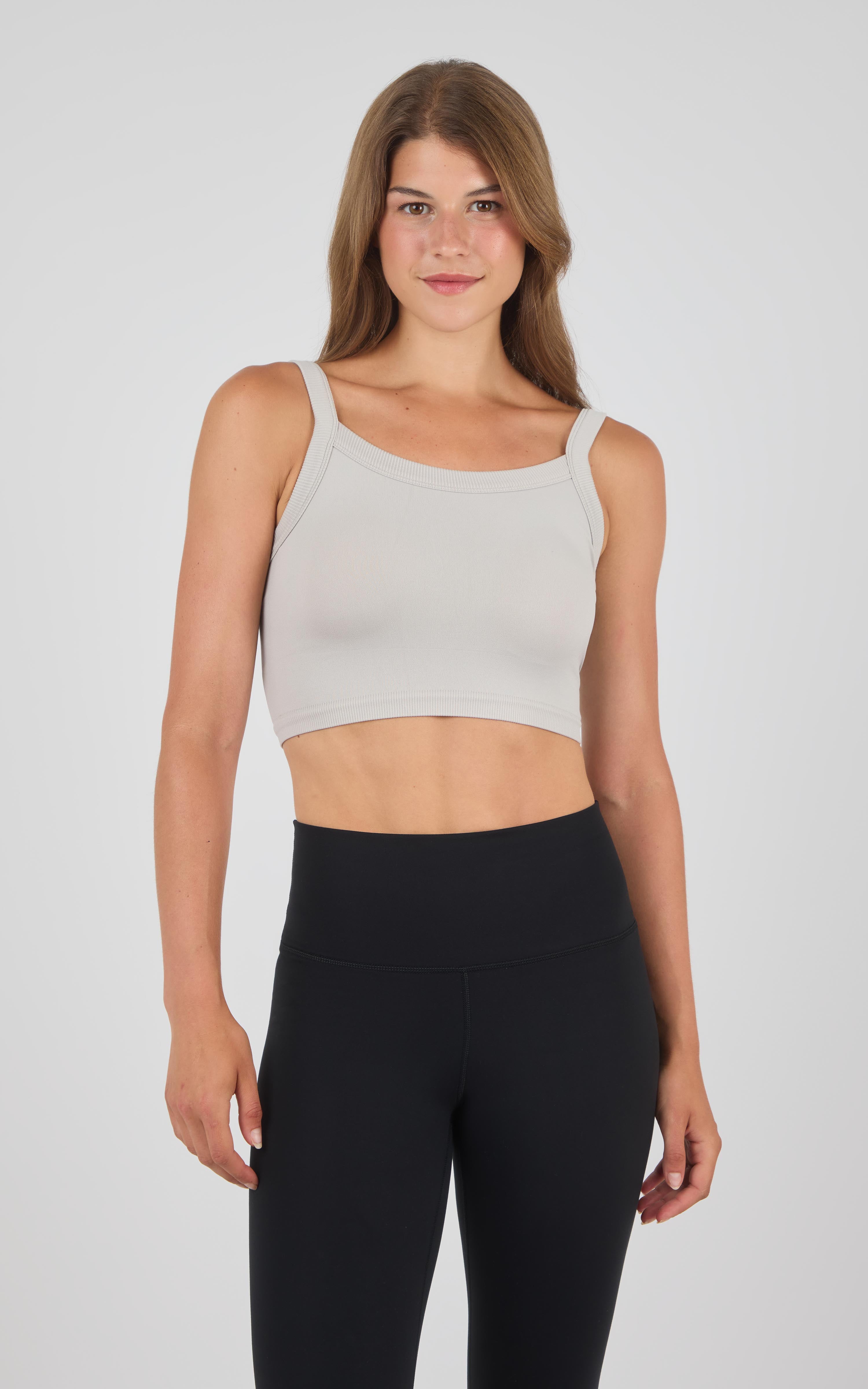 Seamless light beige crop bra tank with wide straps paired with black high-waisted leggings.