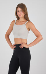 Seamless light beige bra tank with thin straps paired with high-waisted black leggings.