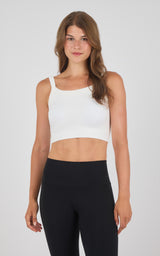 White seamless crop bra tank top with wide straps worn with black high-waisted leggings.