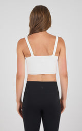 White seamless bra tank with wide straps paired with black high-waisted leggings on a model facing away.