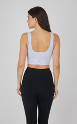 Seamless scooped neck bra in nacreous cloud white, textured fabric, worn with black leggings.
