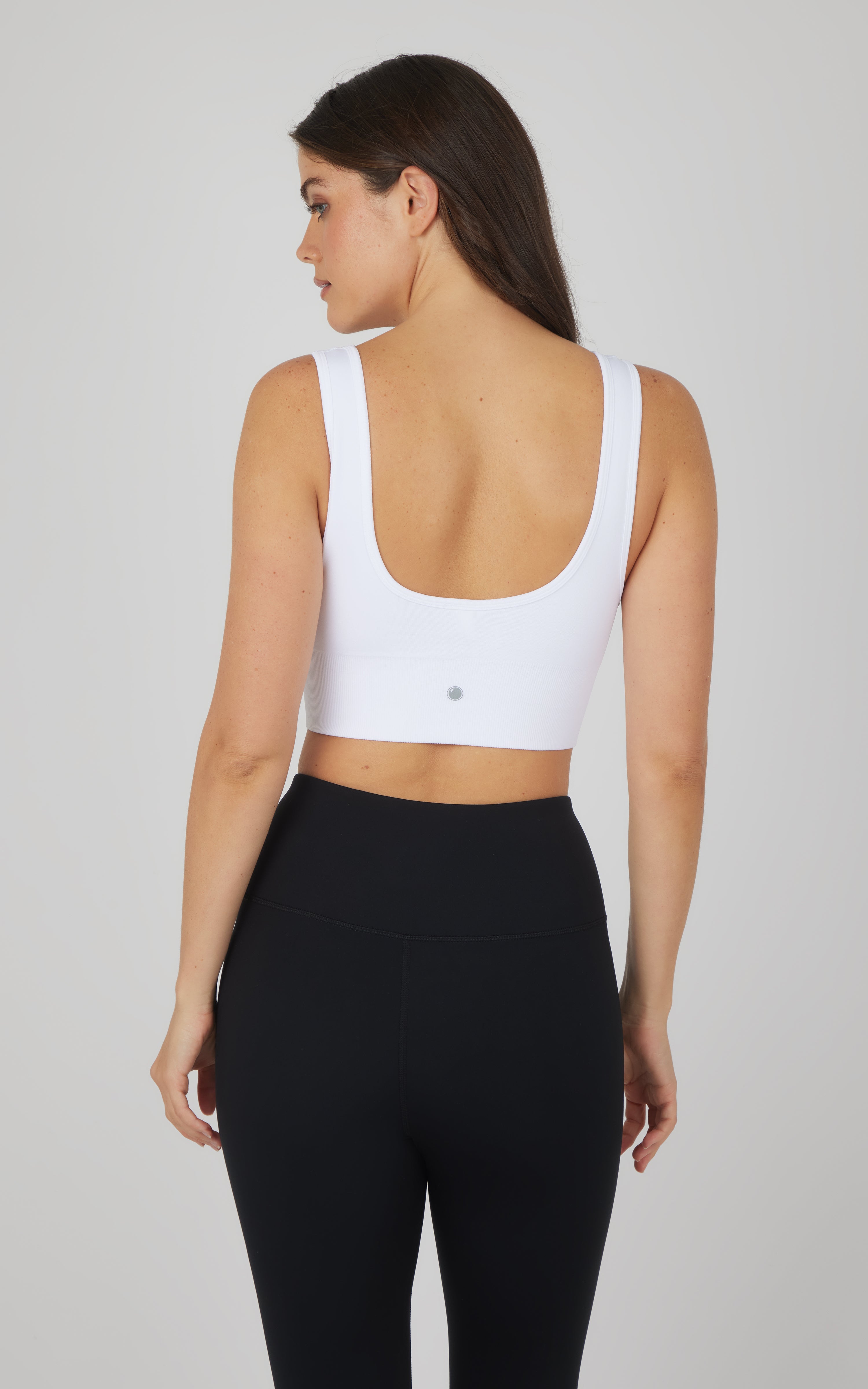 White textured seamless scooped neck bra with wide straps on woman from the back.