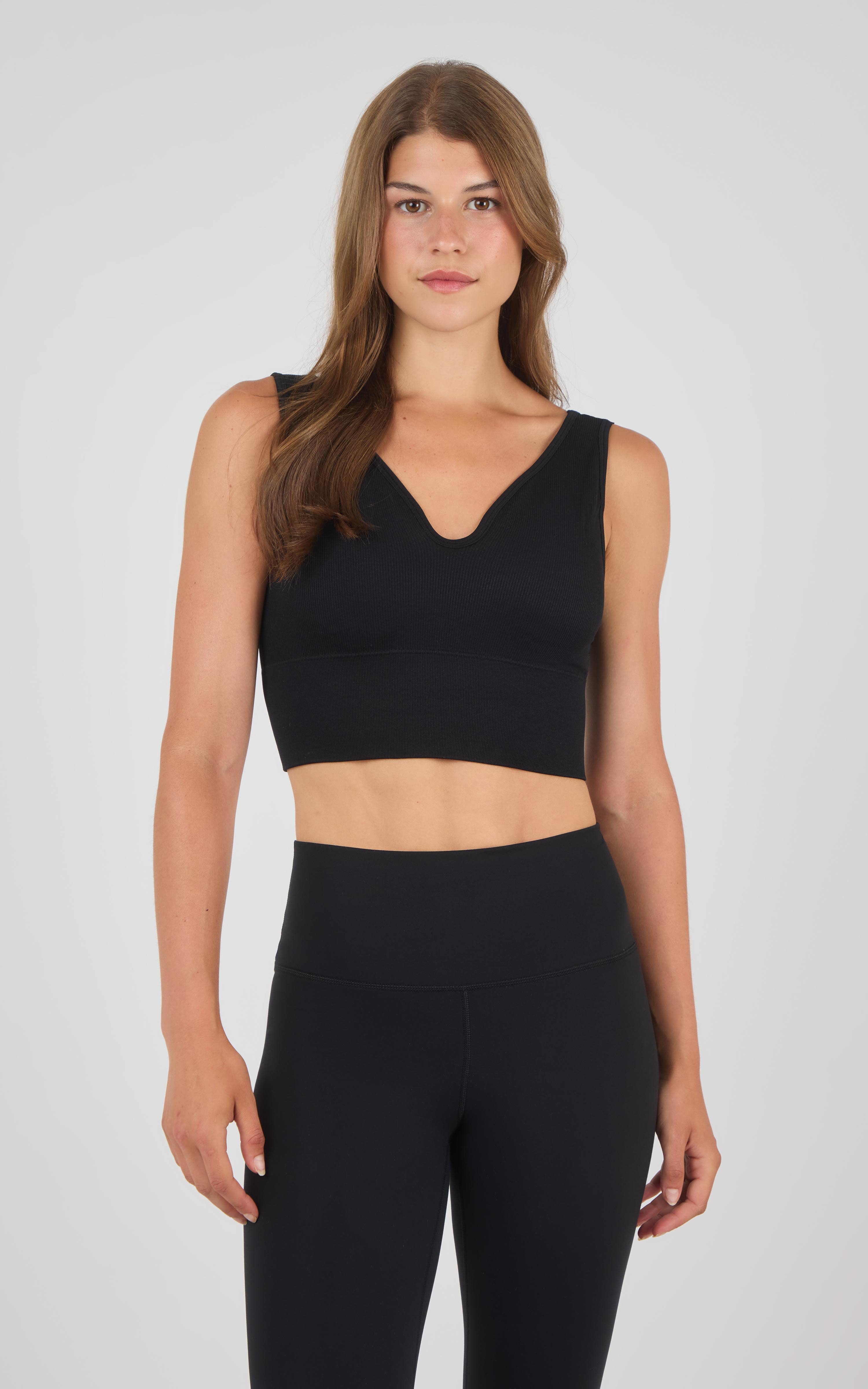 Black seamless crop bra with wide straps and V-neckline on a woman.