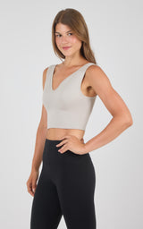 Seamless light beige bra with wide straps and V-neck, worn with black leggings.