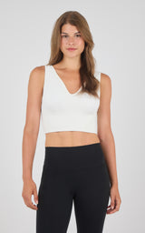 White seamless longline bra top with wide straps and a deep V-neckline, paired with black high-waisted leggings.