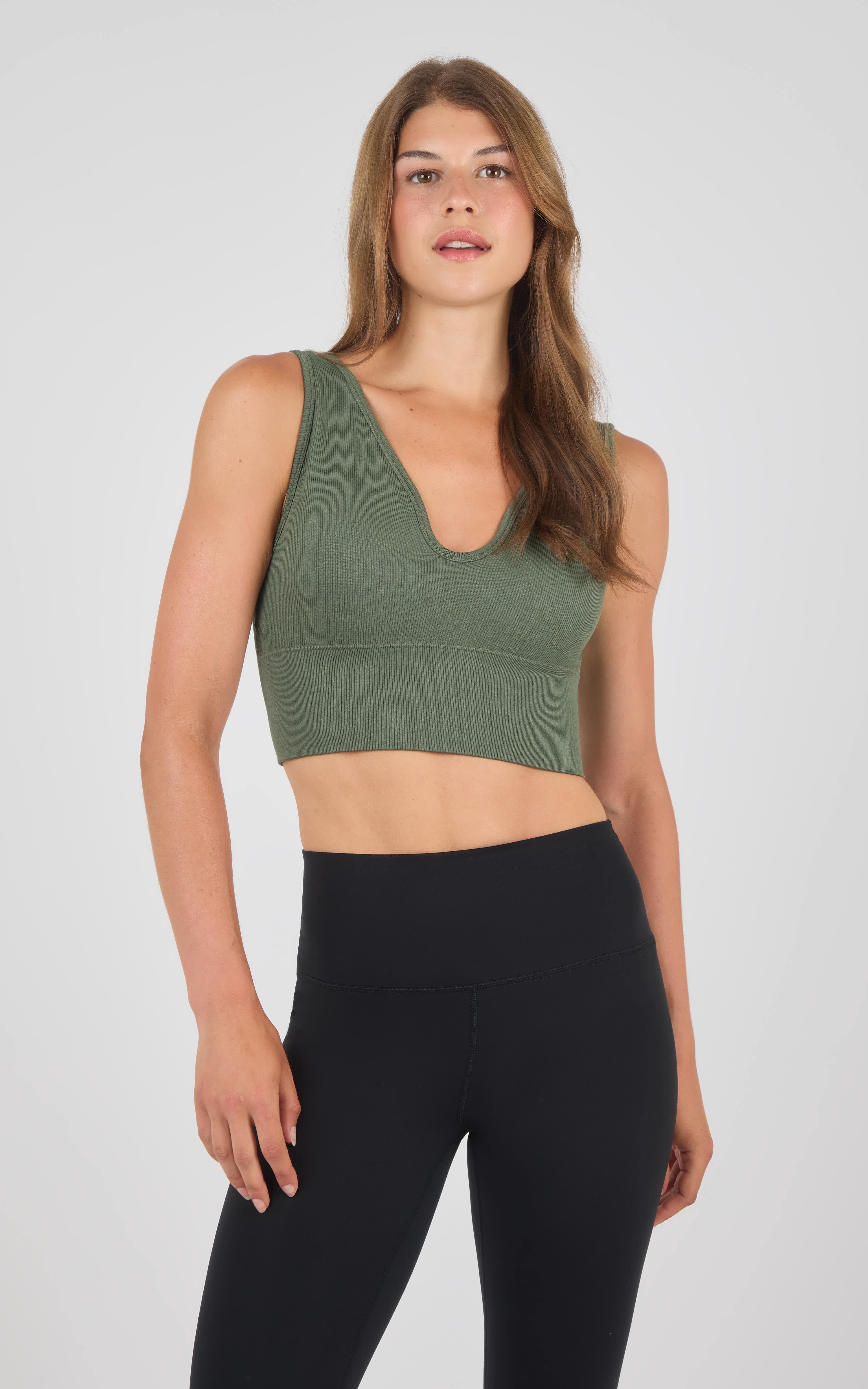 Sleeveless seamless crop bra top in muted green with scoop neckline and ribbed hem.