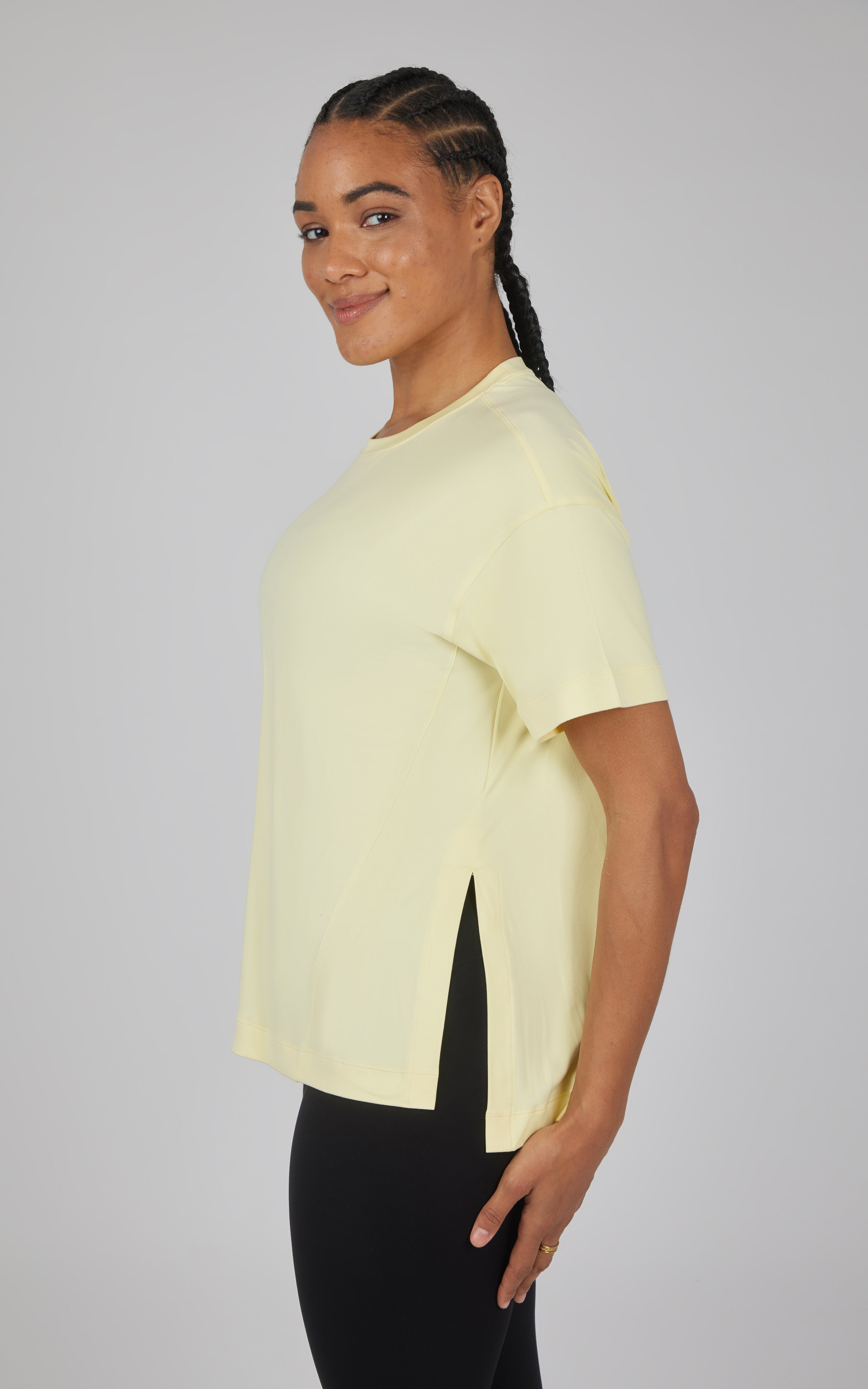 Pale yellow boxy short-sleeve top with a high-low hem and side slits, shown in profile.