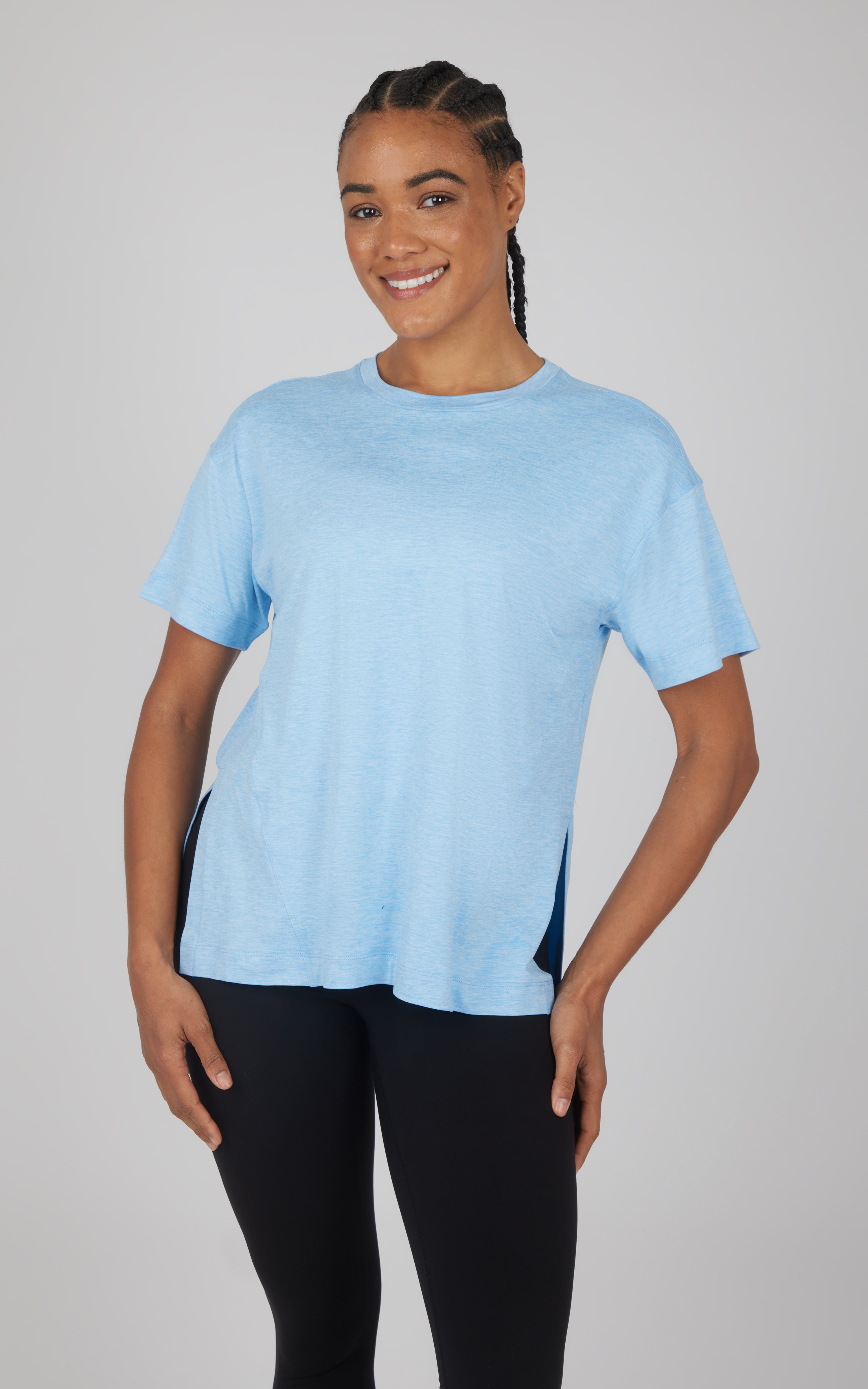 Light blue soft short-sleeve top with a relaxed boxy fit and curved hi-low hem, paired with black leggings.