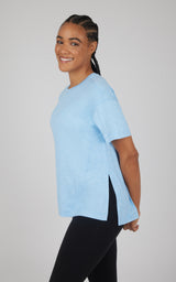 Light blue boxy short-sleeve top with a high-low hem and deep side slits, paired with black leggings.