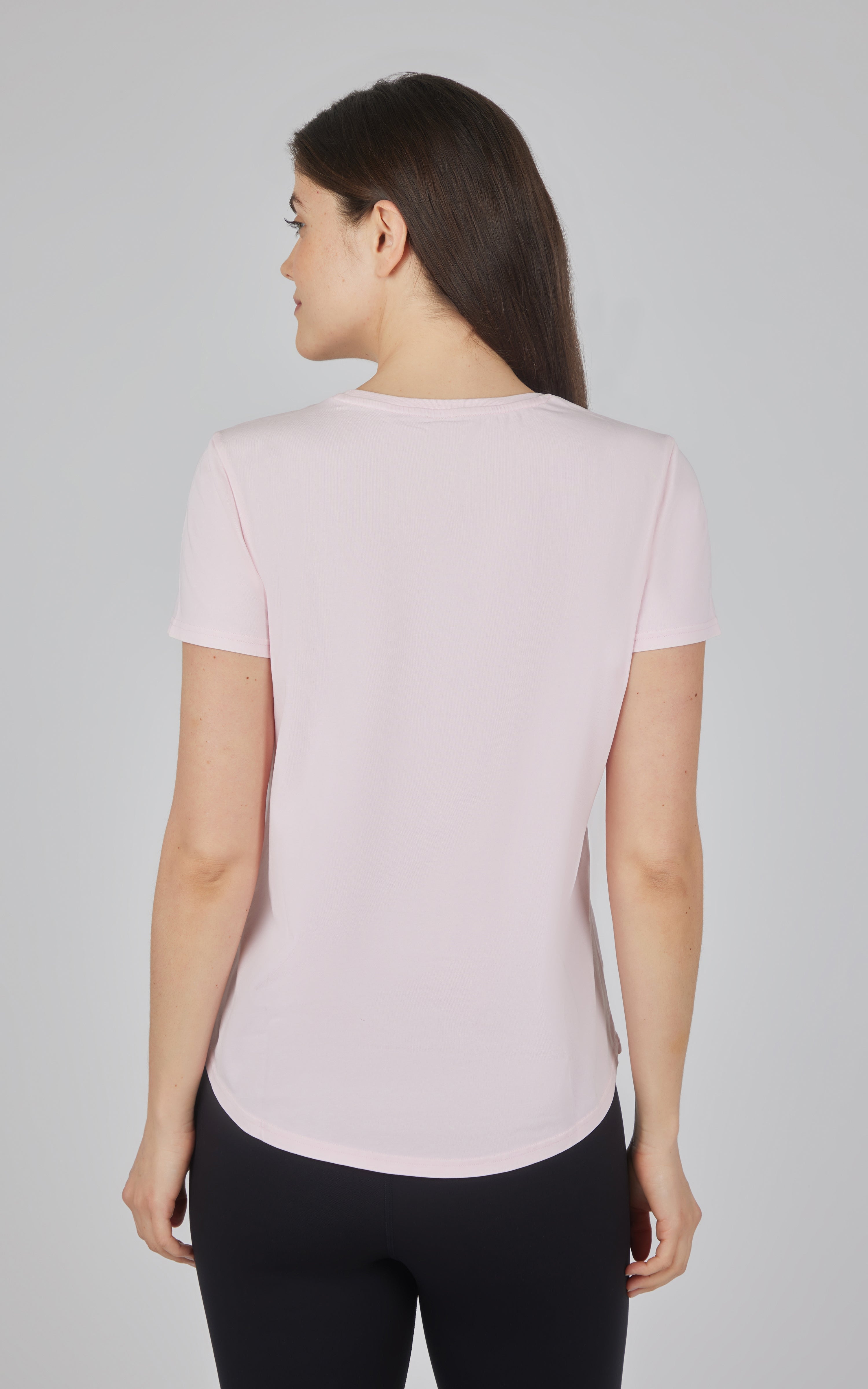 Light pink cotton jersey crew neck tee with short sleeves and curved hem on a woman.