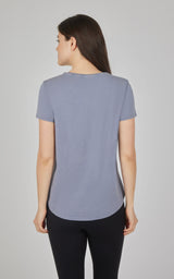 Women's short-sleeve crew neck tee in soft acid wash blue with curved hem, back view.