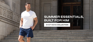 Man in white t-shirt and blue shorts standing on steps "summer essentials built for him shop mens collection"