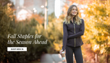 Woman wearing a brown activewear jacket and leggings walking along a tree-lined path surrounded by autumn foliage, with text reading “Fall Staples for the Season Ahead” and a “Shop New In” button.

