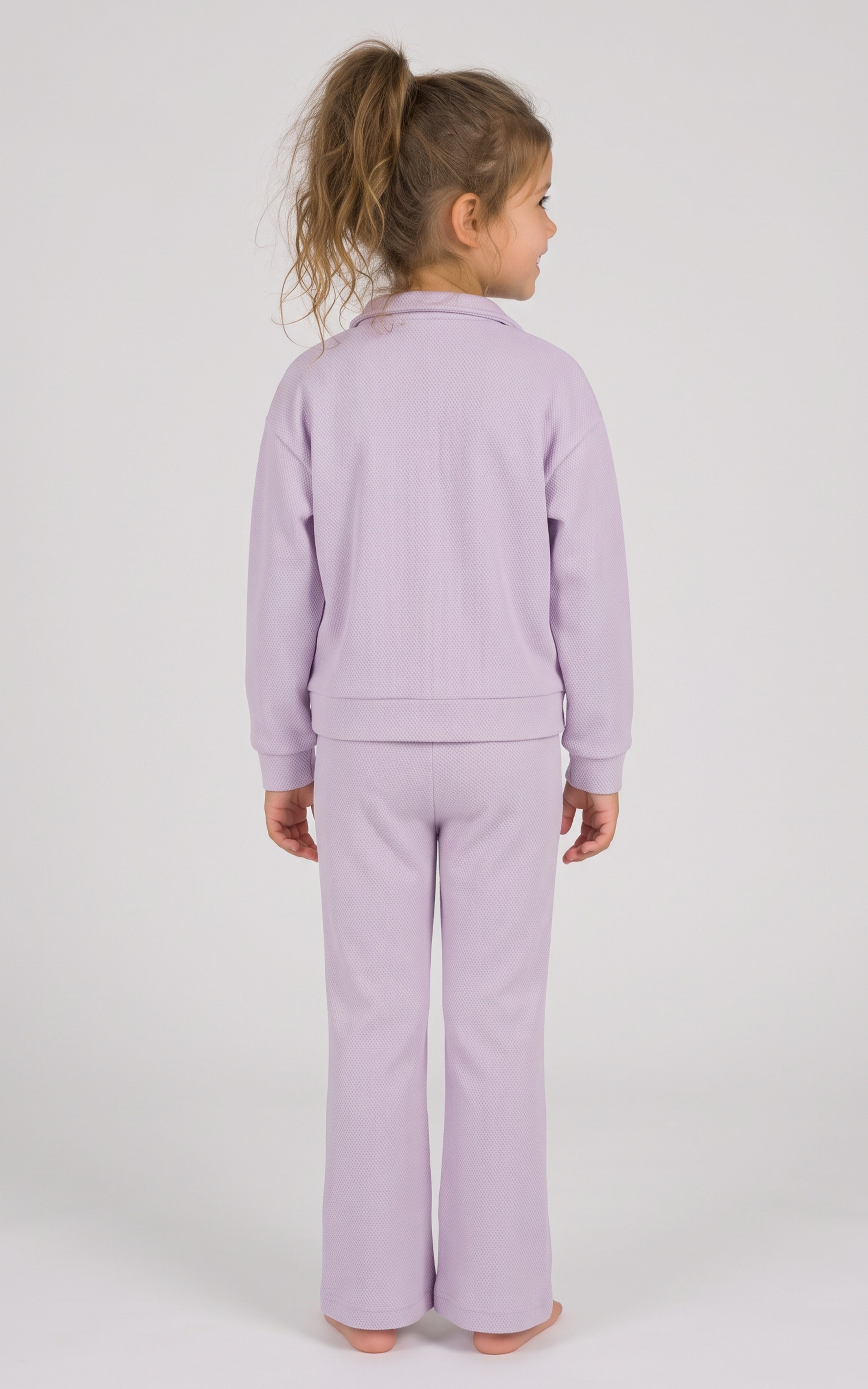 Back view of a toddler girl wearing a lavender half-zip sweatshirt and matching slim-fit flare pants.