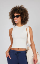 White cotton mock neck tank top with sleeveless design, fitted waist, and smooth texture.
