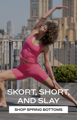 A women in a pink activewear set, in a yoga pose with a text overlay " Skort, short, and slay. Shop Spring Bottoms"