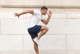 Man in athletic wear posing against a light stone wall