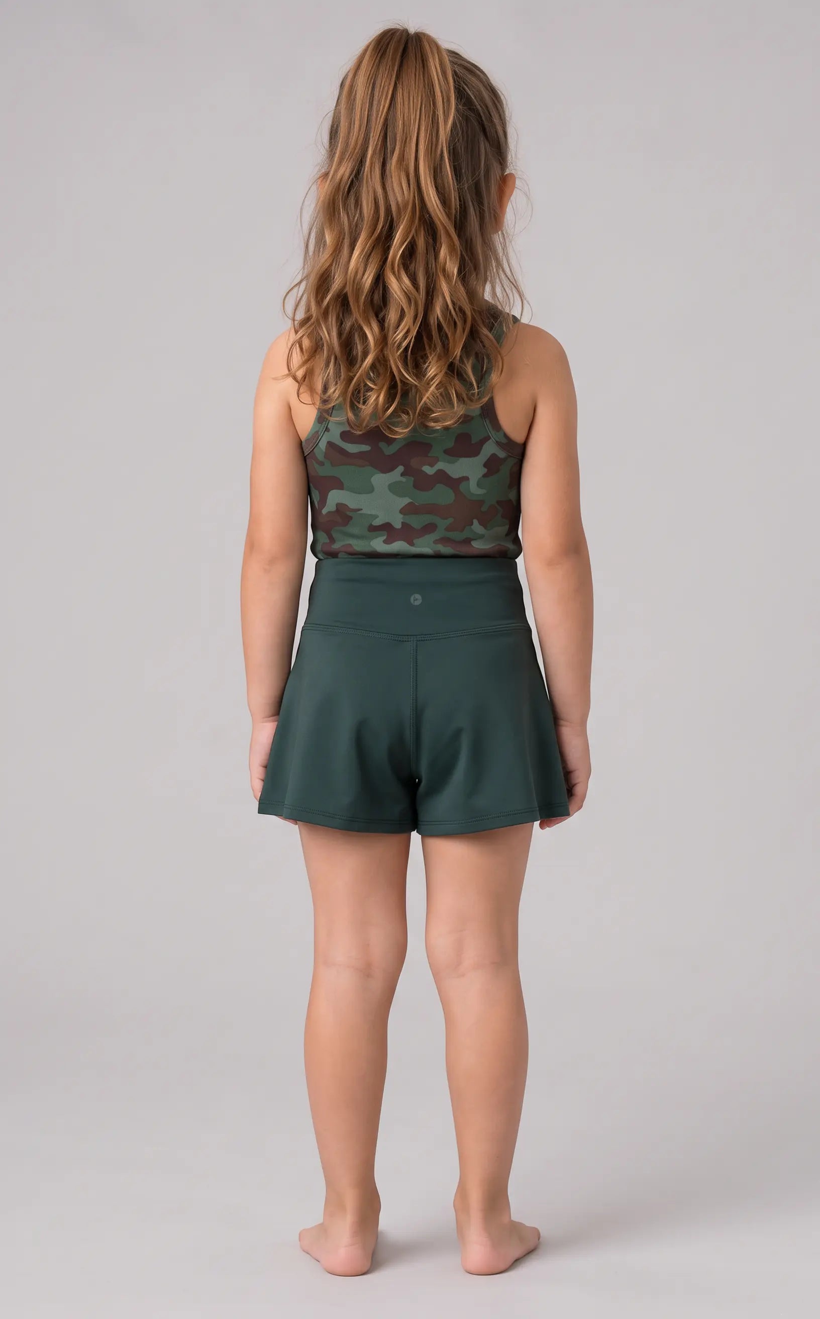 Back view of a girl wearing a dark teal tank top with a subtle pattern and matching crossover shorts.