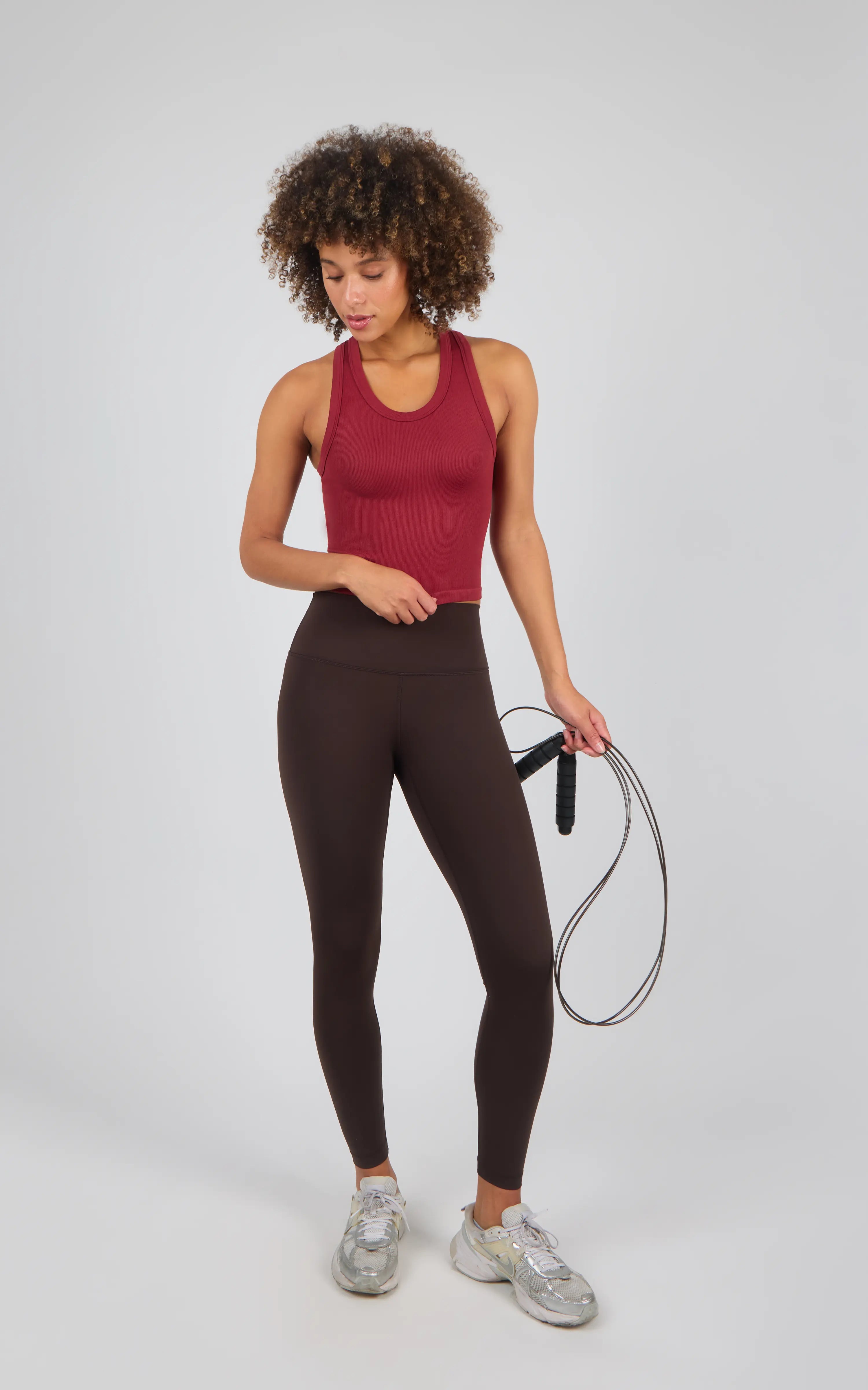 Dark chocolate brown high-waisted leggings with a smooth, stretchy fit paired with a sleeveless burgundy workout tank and.