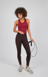 Dark chocolate brown high-waisted leggings with a smooth, stretchy fit paired with a sleeveless burgundy workout tank and.