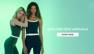 Two women in matching outfits with promotional text on a green background "Explore New Arrivals Shop Now"