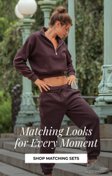 Woman wearing a matching burgundy cropped sweatshirt and jogger set outdoors near decorative park lamps, with text reading “Matching Looks for Every Moment” and a “Shop Matching Sets” button.