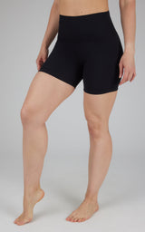 Black high-waist 5-inch classic biker shorts on a model with bare feet and light skin tone.